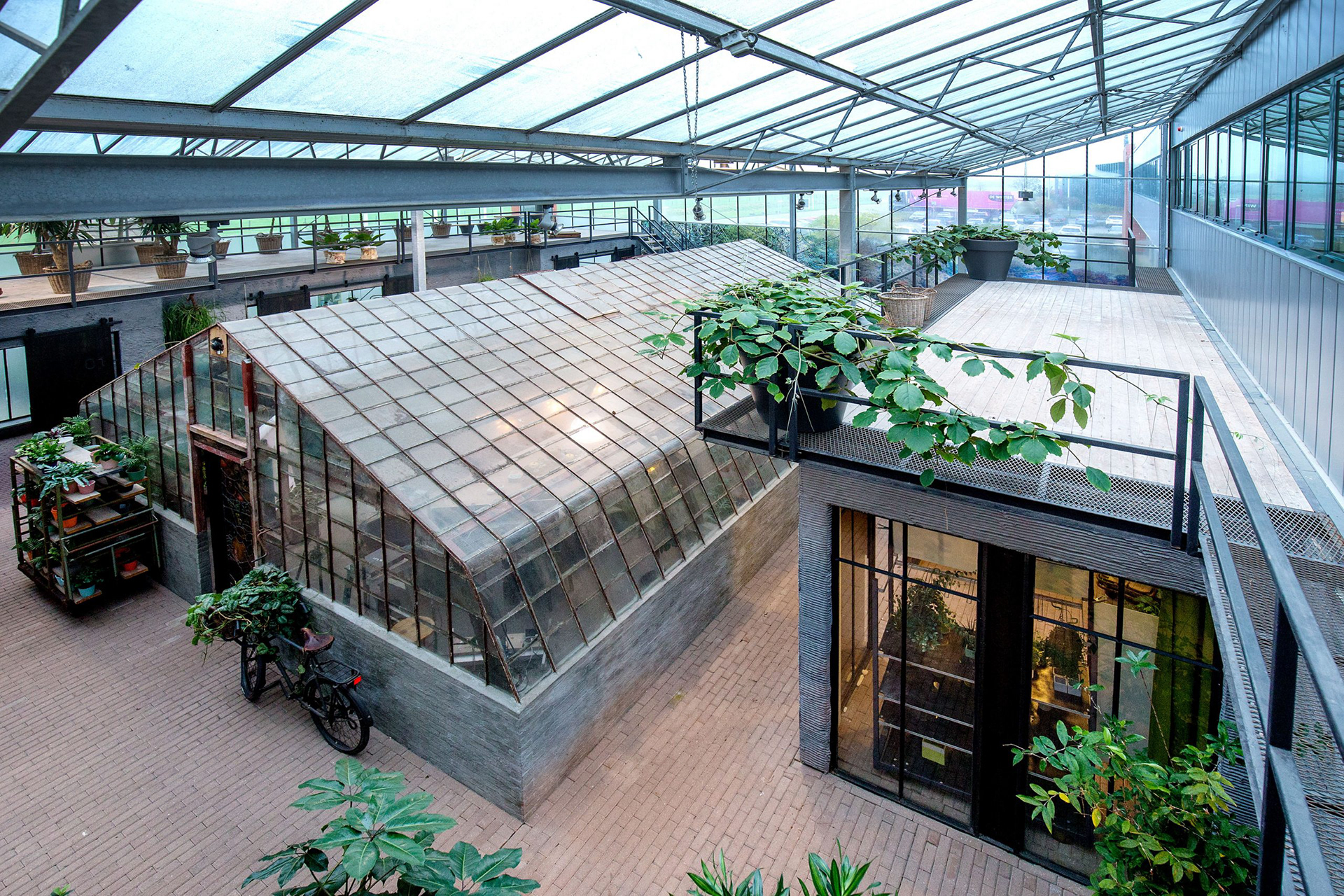 Lichte hal met glazen kas, plantenwagentjes en terras bij HortiFlora